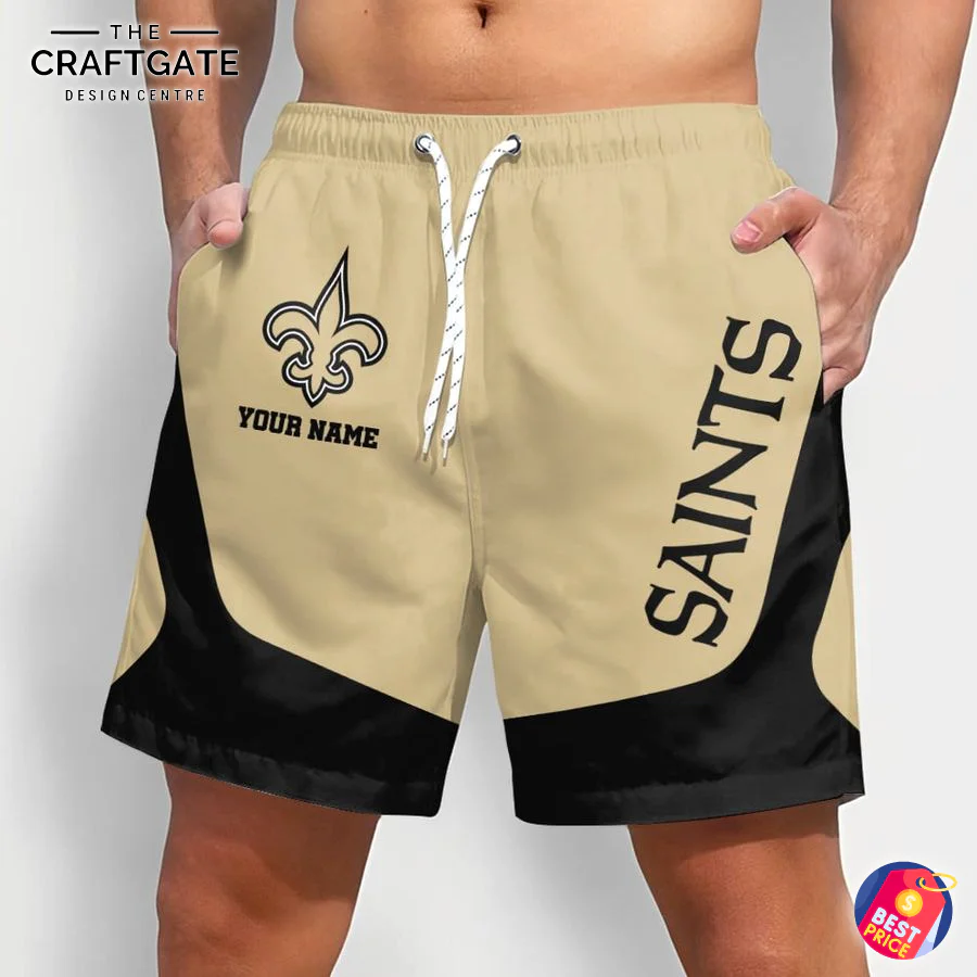 Personalized New Orleans Saints NFL Shorts for Fans (Front View) A man models custom New Orleans Saints shorts from the front, featuring the team logo, a space for a name, and a gold and black design.
