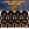 Group display of black "First Responder Night 2025" hoodies showing front and back views with firefighter crest, NFL shield background, American flag stripe graphics and orange/gold flame accents featuring team names like Bills, Eagles, Lions and 49ers