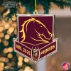 A Brisbane Broncos 2025 NRL Premiers acrylic ornament hanging from a Christmas tree with warm bokeh lights in the background.