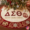 An elegant ivory and red velvet tree skirt under a Christmas tree, featuring embroidered Delta Sigma Theta letters and crest with jewels.