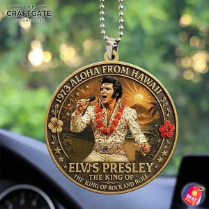 A detailed close-up of the Elvis Presley Aloha From Hawaii acrylic ornament hanging in a car with a blurry green background.