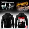 A promotional image for the John Carpenter 2025 tour, showing the front and back of the official hoodie with The Thing movie poster art.