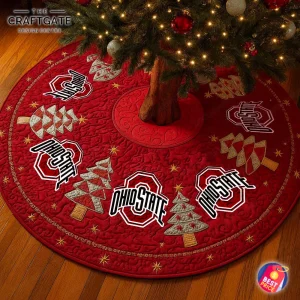 A red quilted Ohio State Buckeyes tree skirt under a lit Christmas tree, featuring team logos and embroidered holiday designs.
