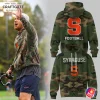 A coach wears the Syracuse Orange camo hoodie, shown next to the front and back views of the military-style sweatshirt.